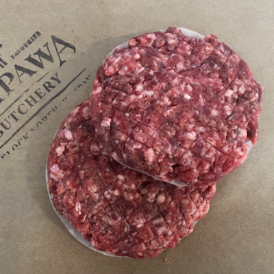 Two uncooked lamb patties sit on some brown paper with a Waipawa Butchery stamp on it.