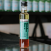 A bottle of Maison Therese apple cider vinaigrette sits on a reflective bench with out of focus bottles behind it.