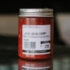 A jar of Waipawa Butchery Spicy Indian Chutney sits on a reflective bench with a blurred background.