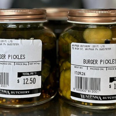 2 Jars of Waipawa Butchery Burger Pickles sit on top of the counter in the store.